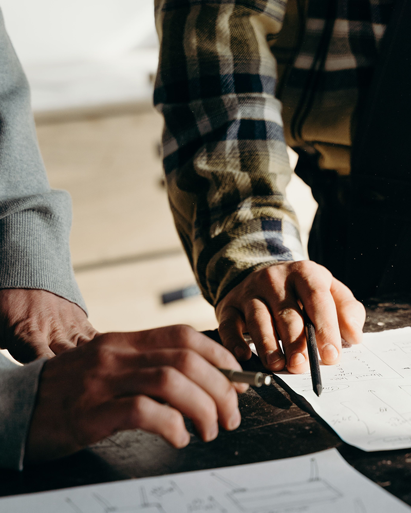Deux personnes penchées sur des plans, un crayon à la main, pendant l'étude d'un projet